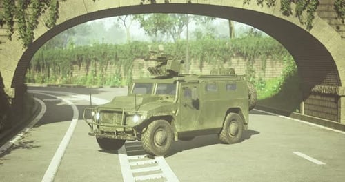 Military Vehicle Navigating a Winding Road Under a Stone Archway
