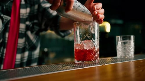 Bartender Adds Ice to Cocktail at Bar