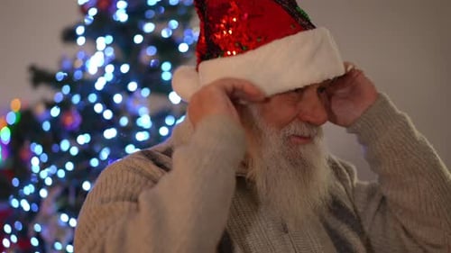 Senior Man Puts on Santa Hat Indoors