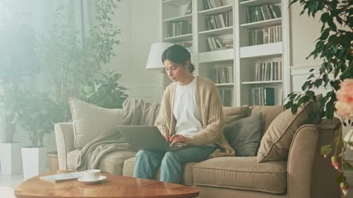 Woman Using Laptop on Couch in Bright Living Room