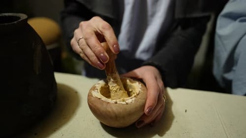 Woman Grinding Ingredients in Bowl with Pestle