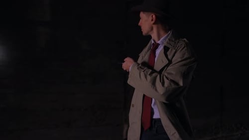 Walking Around Looking Around Searching Detective in a Raincoat and Hat with a Flashlight Looking