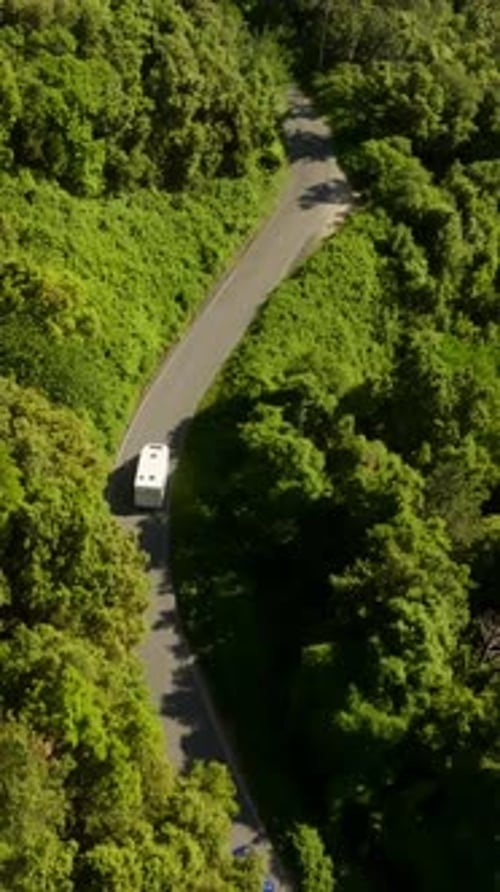 Vertical drone shot tilting over a RV driving on a high altitude road in Italy