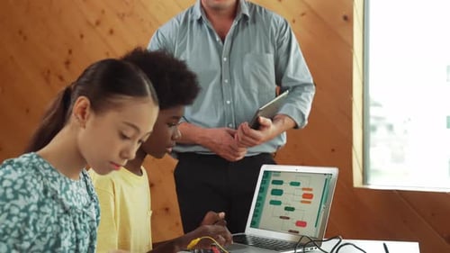 Der Lehrer steht, während er das Programmieren und die Roboterkonstruktion erklärt. Erbauung