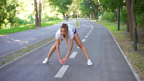 Happy Sporty Woman Jogger Doing Stretching Exercise on Road in Park