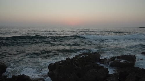 Sea Waves Crushing on a Rocky Beach at Sunset