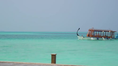 Traditional Wooden Maldivian Boat coming into dock across turquoise blue water