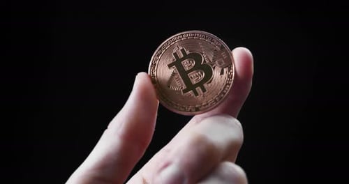 Bitcoin Coin Held by Hand on Black Background Representing Cryptocurrency