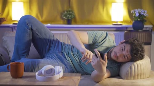 Homme accro au téléphone à la maison la nuit.