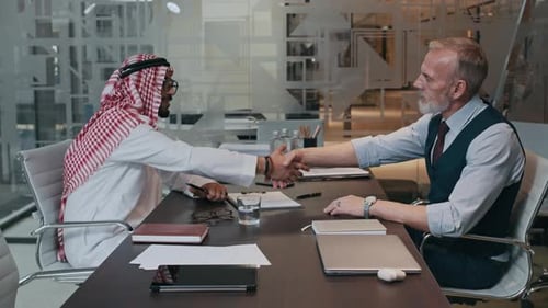 Diverse Entrepreneurs Shaking Hands at Table in Modern Office