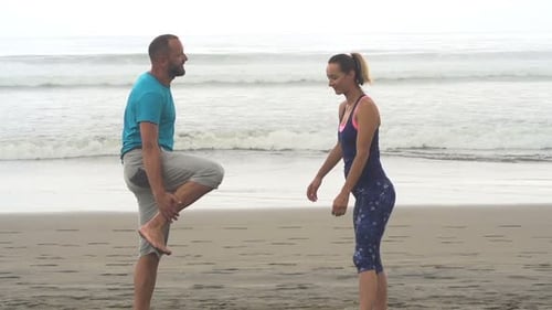 Fit Couple Talking and Stretching Body on Beach Adult