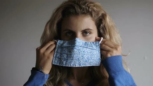 Woman Puts on a Protective Blue Face Mask