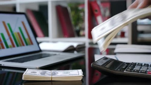 Stacking Money Near Laptop and Calculator in Office