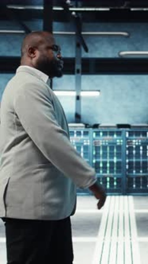 Vertical Video Employee Walking in High Tech Data Center with Hardware Used to Host Websites