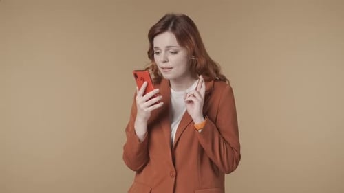 Medium Isolated Video of a Woman Holding a Smartphone in Her Hand Crossing Fingers Waiting for the