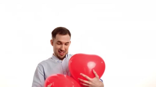 Happy Man Holds Two Heart Balloons and Smiles