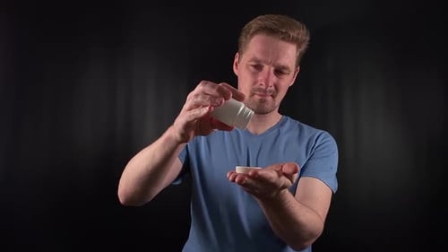 Man Taking Pill From White Bottle