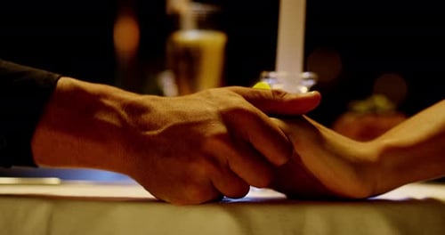 Couple Holding Hands During Romantic Candlelight Dinner