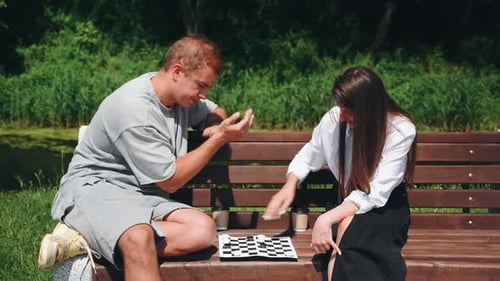 A Cheerful Couple Happily Plays Checkers on a Cozy Park Bench Creating a Delightful Atmosphere