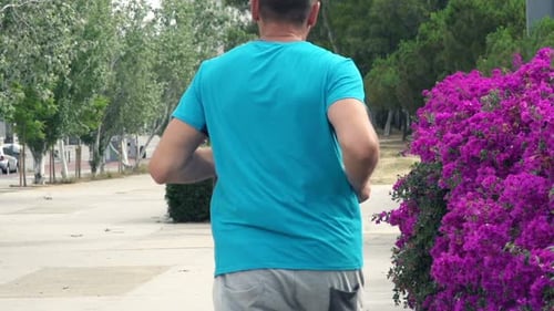 Young man jogging alone at dawn in city park super slow motion