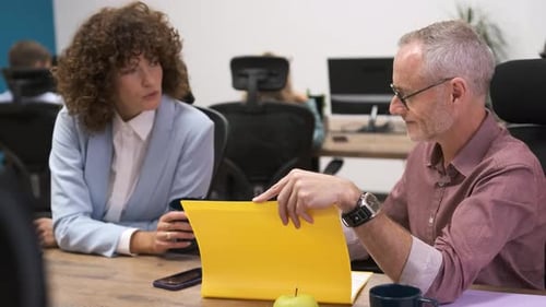 Happy Mature Businessman Discussing with Female Colleague in Office