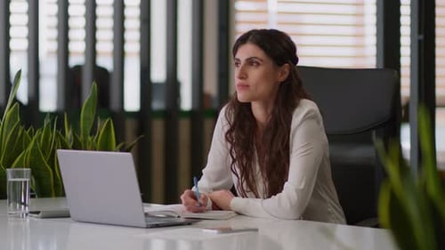 Young Woman Writing at Desk in Modern Office