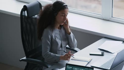 Operator Taking Notes in Notepad and Speaking to Online Clients in Office