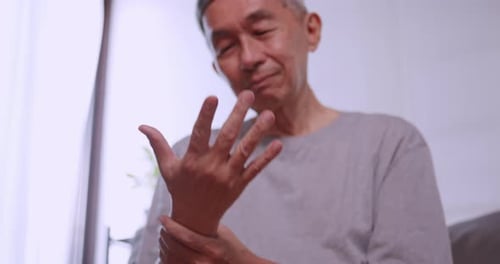 Senior Man Massages Sore Wrist at Home