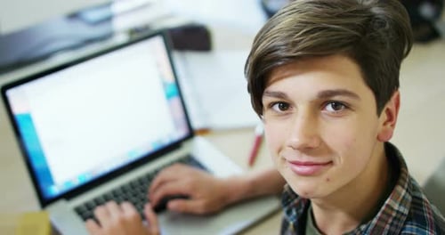 young boy studying on computer and earphones and looking to the camera in soft slow motion, school
