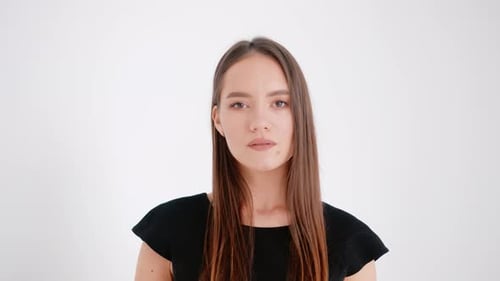 Portrait of a Beautiful Smiling Young Girl in a Black Dress on a White Studio Background