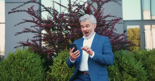 Excited Man in Suit with Phone Celebrates Success