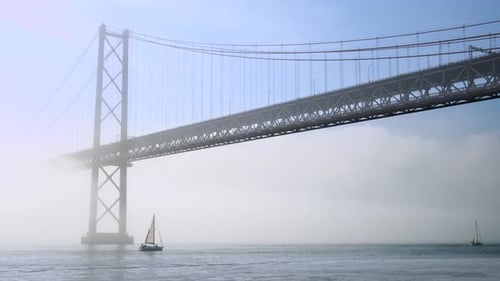 Voiliers passant sous le pont du 25 avril dans le brouillard sur le Tage, Lisbonne, Portugal