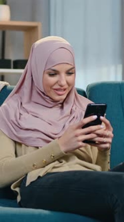 Smiling Woman Relaxing on Couch and Using Phone