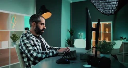 Professional freelance photographer writing emails for his clients, sitting behind desk working on d