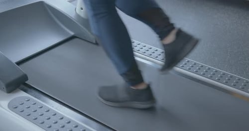 Cámara lenta de cerca de las piernas de una mujer corriendo en una cinta de correr