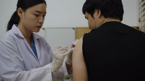 Woman Administers Injection to Arm in Clinical Setting