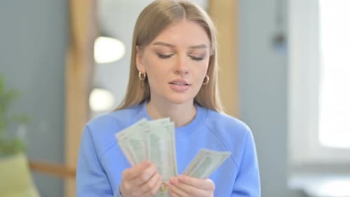 Woman Counting Dollars in Creative Office
