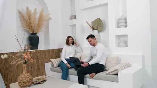 Woman Talking on Phone, Man Using Laptop