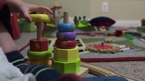 Close up low angle shot of a toddler playing with colored wooden blocks of different shapes.