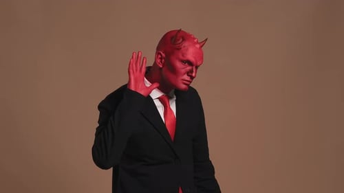 Empresario del Diablo Rojo escuchando y señalando sobre fondo marrón