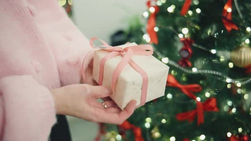 Festive Woman Unwraps Christmas Present near Decorated Tree