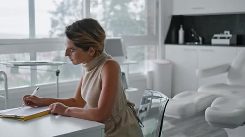 Confident woman fills agreement form for rejuvenating facial treatment at luxury clinic