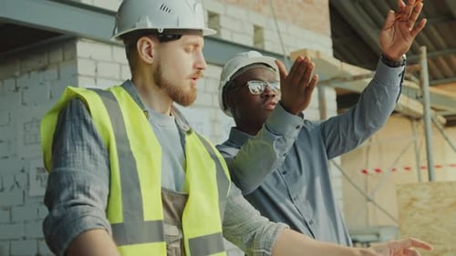 Architect Explaining Building Plan to Contractor at Construction Site