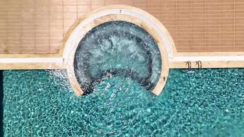 Aerial View A Luxurious Pool Area with Clear Water Relaxing Jacuzzi and Fun Slides Defines This