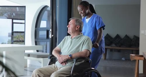 Man in Wheelchair Pushed by Caregiver in Home