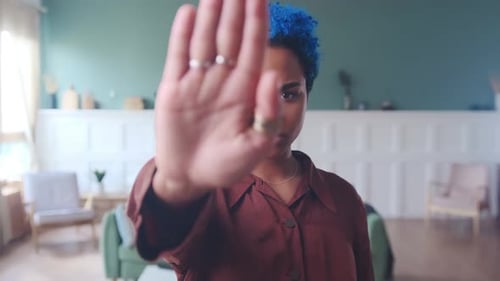 Young Adult Raises Hand in Stop Gesture Indoors