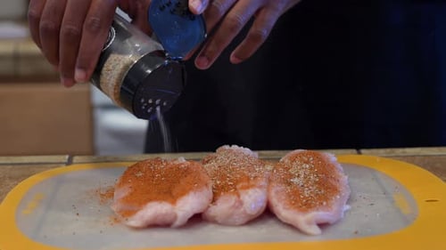 Seasoning Chicken in Kitchen for Meal Preparation