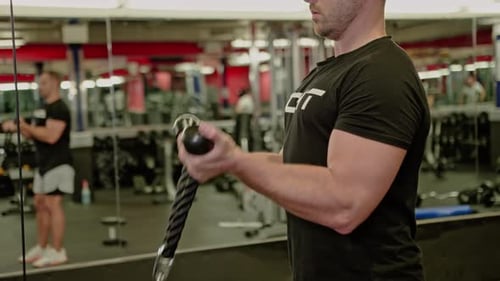 Man Doing Bicep Curls on Cable Machine in Gym
