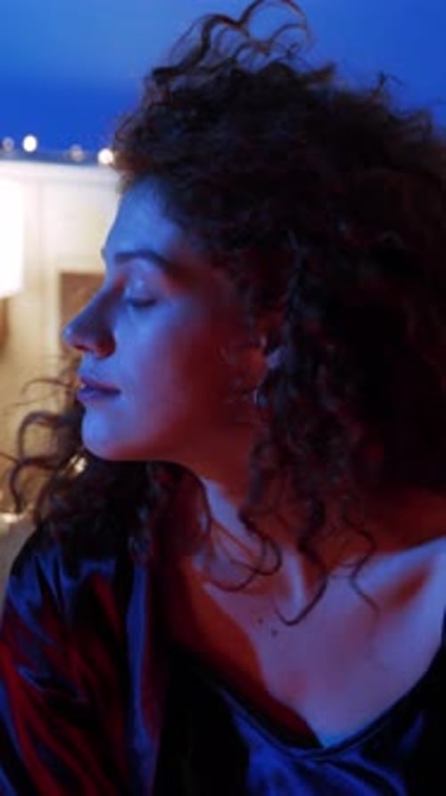 Woman with Curly Hair Posing in Dim Light