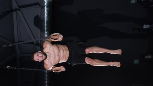 Vertical Video Male Bodybuilder or Exerciser is Working Out on a Rings in the Gym